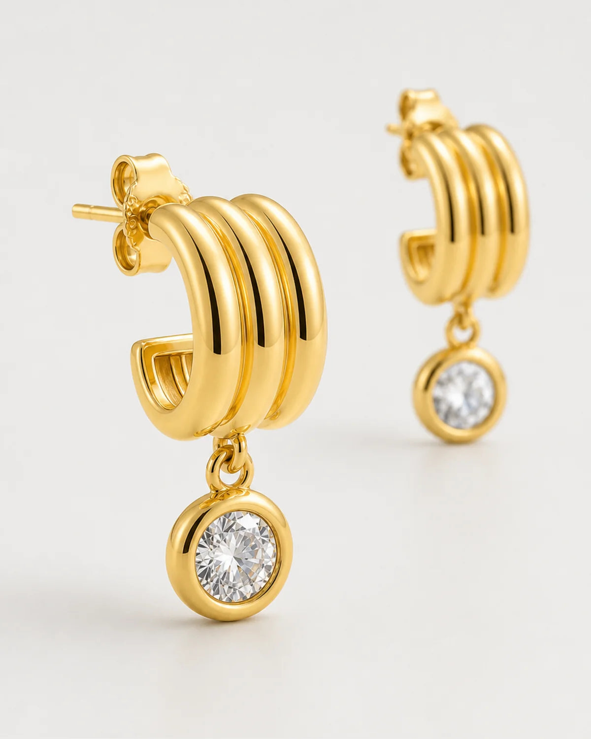 Three-quarter macro of an Astra three-arc mini hoop and round bezel zircon drop