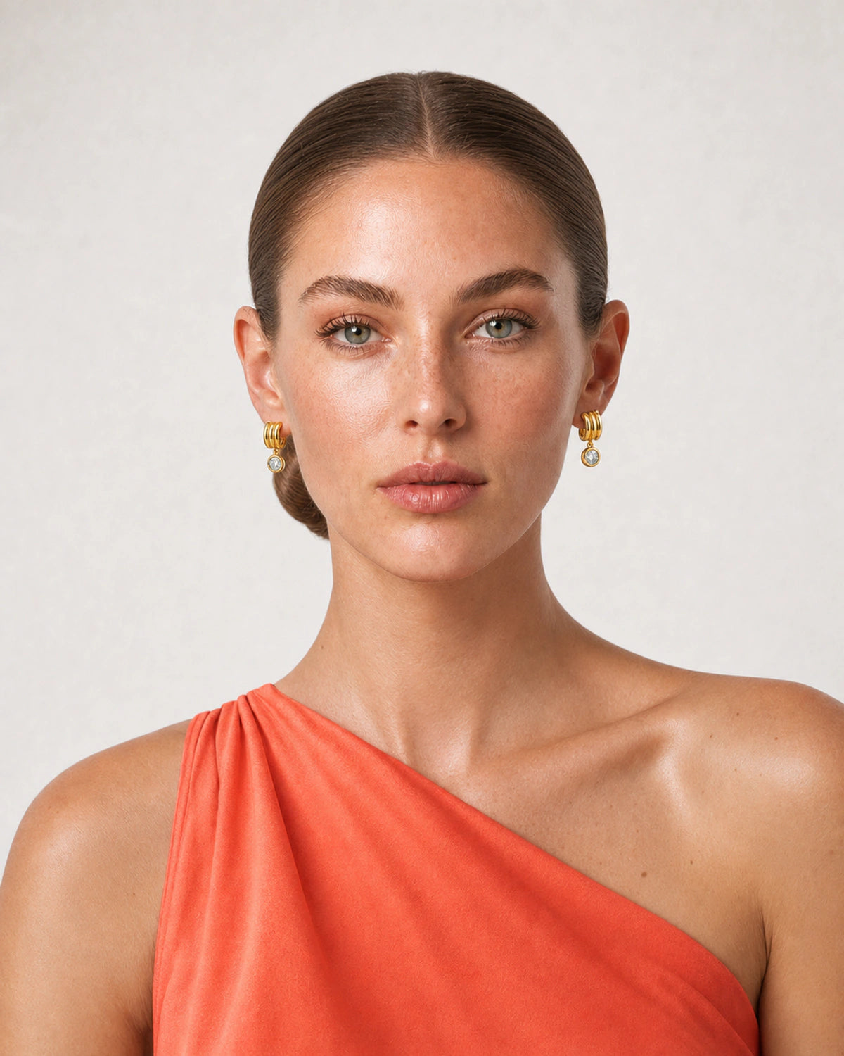 Model in a coral Positano silk top wearing Astra triple arc zircon earrings