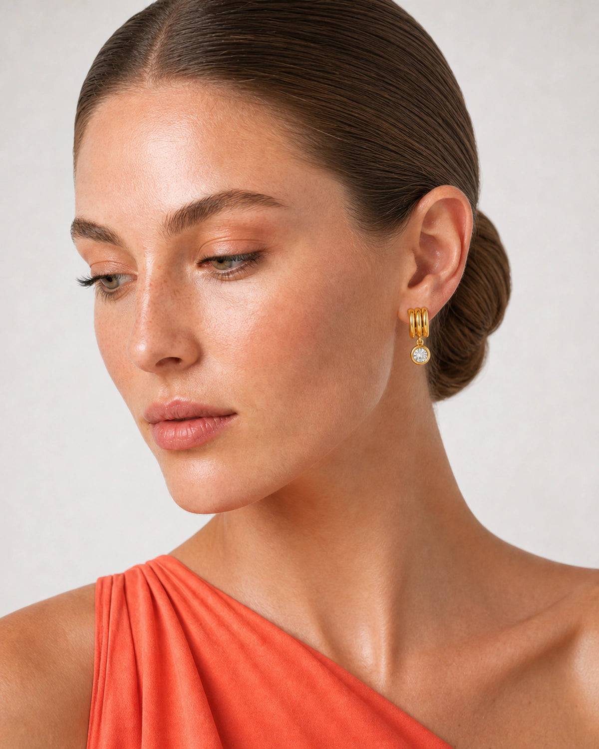 Close wearing view of an Astra three-arc earring and round bezel zircon