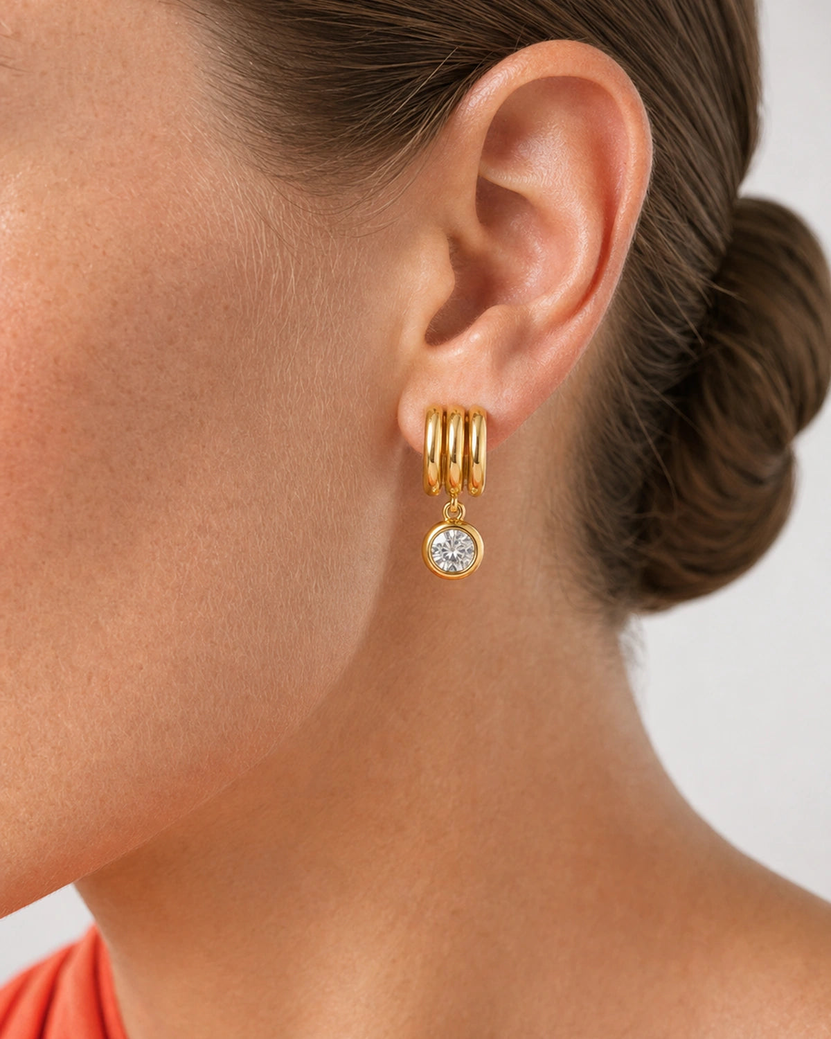 Extreme ear macro of the Astra three gold arcs and round bezel zircon