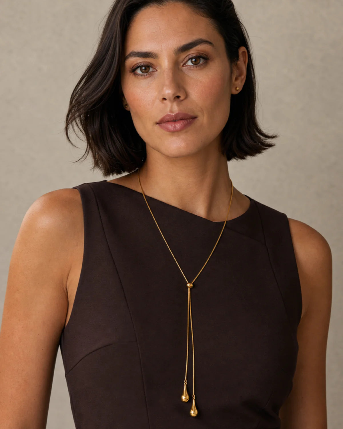 Bob-haired model wearing the Aurelia droplet lariat with a poised direct gaze