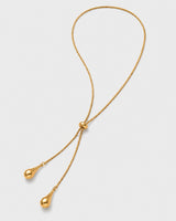 Aurelia gold droplet lariat necklace on warm soft ivory
