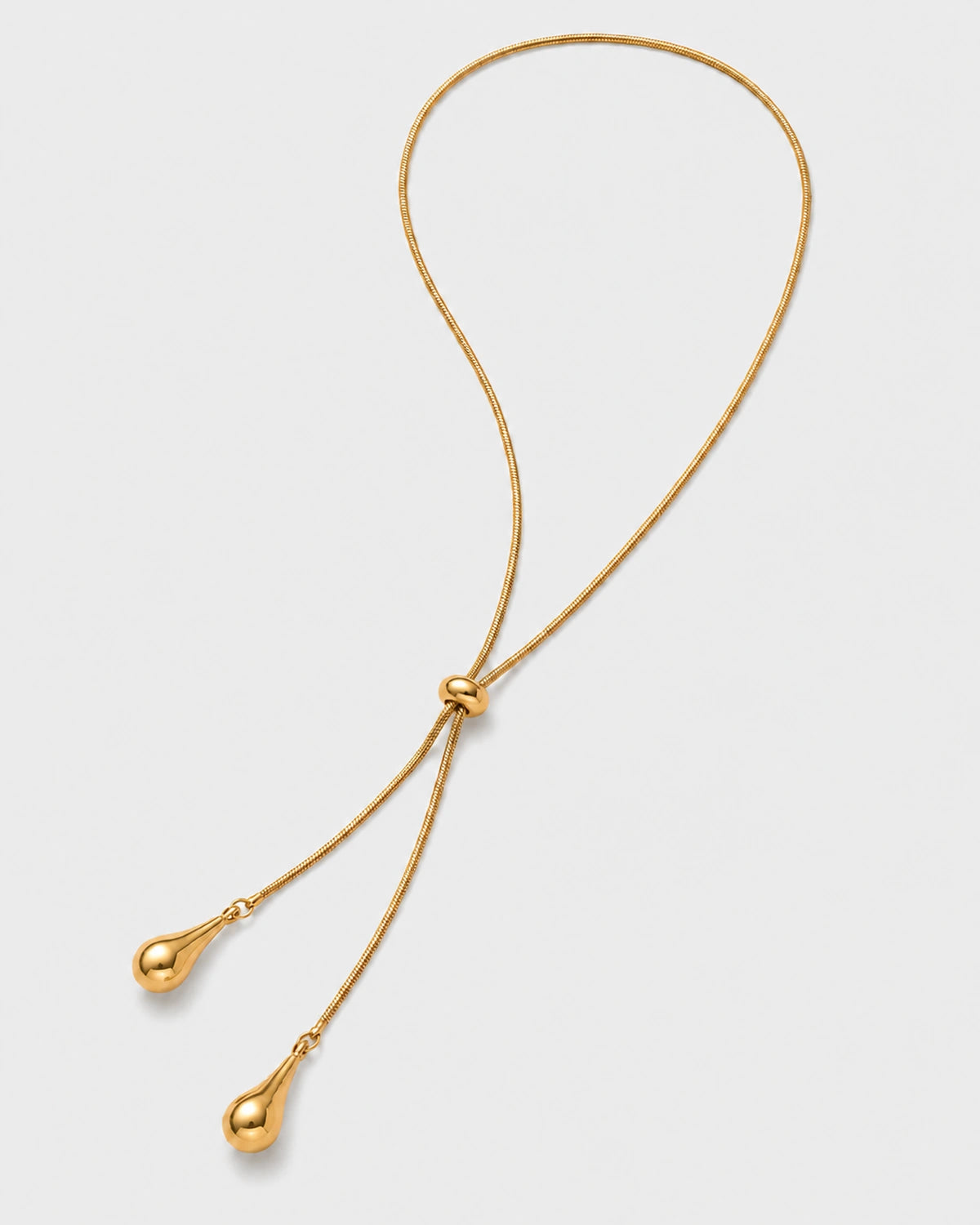 Aurelia gold droplet lariat necklace on warm soft ivory