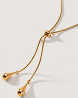 Macro detail of the Aurelia ring slider and polished teardrop charms on limestone