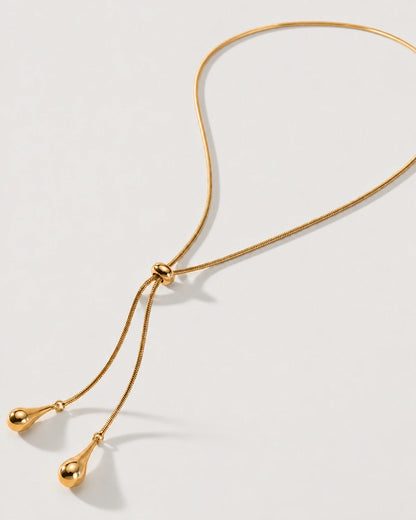 Aurelia gold droplet lariat necklace on a sculptural ivory curve