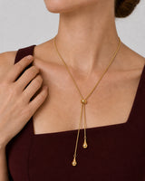 Aurelia droplet lariat worn with a natural hand near the outer collarbone