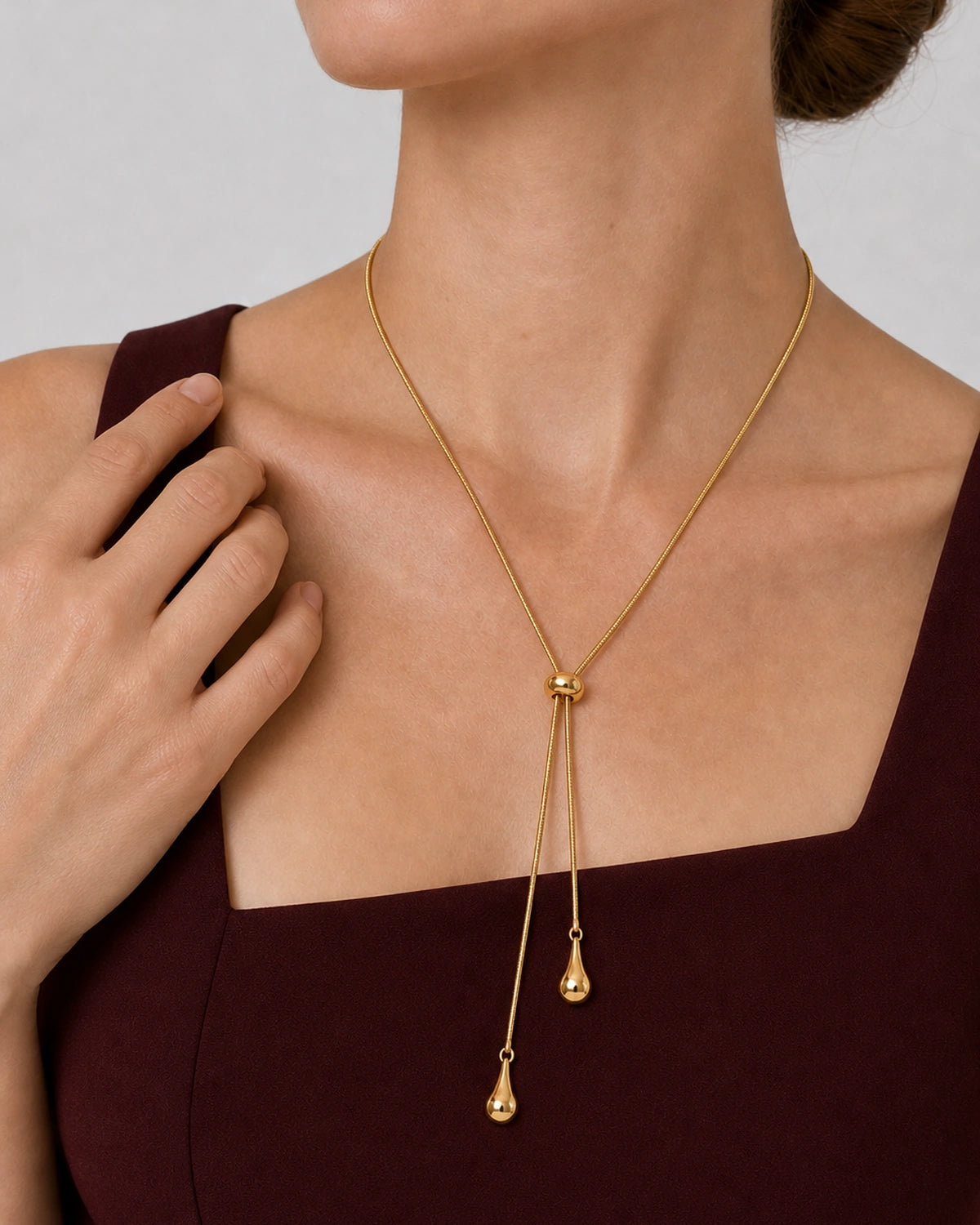 Aurelia droplet lariat worn with a natural hand near the outer collarbone