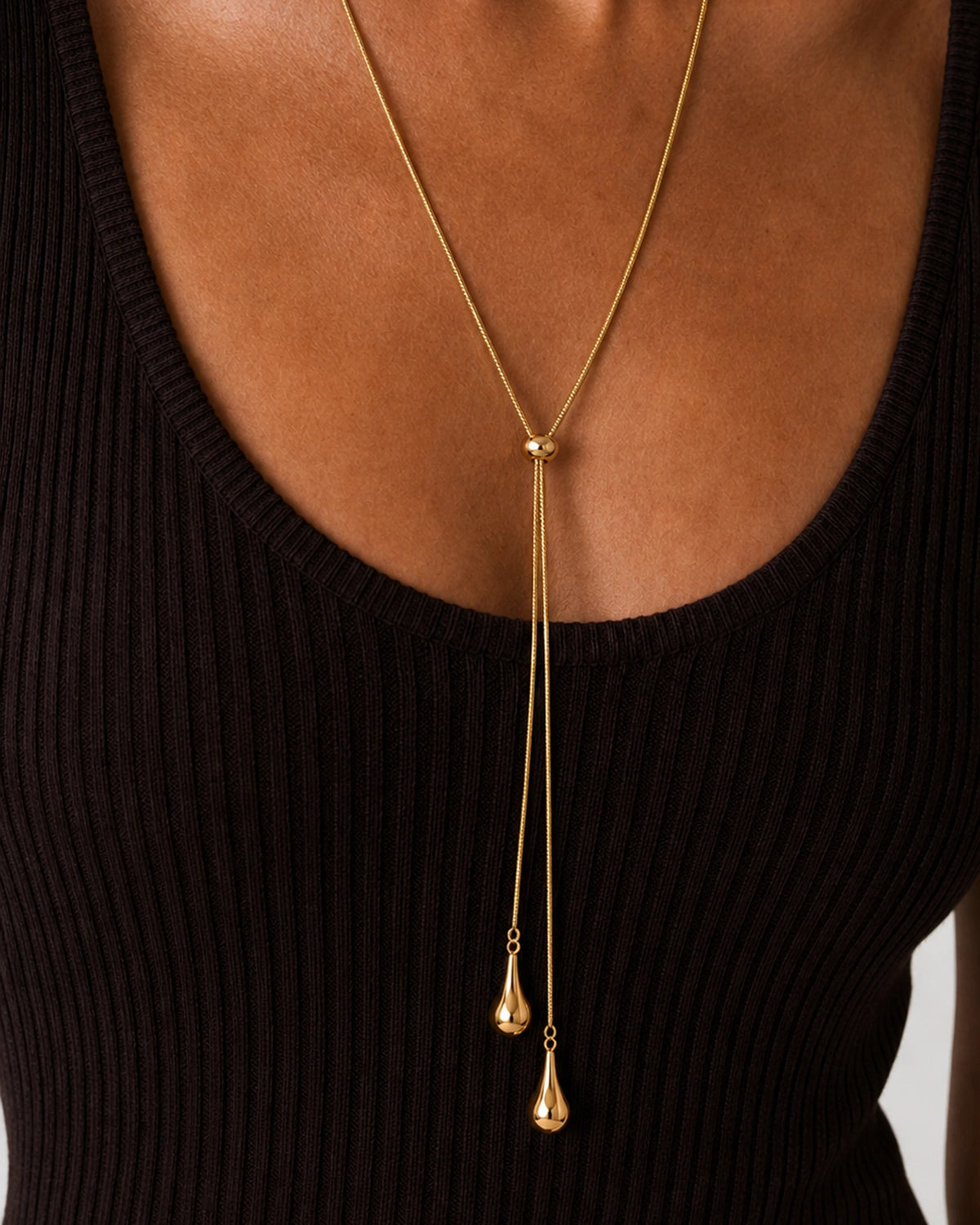 On-body macro of the Aurelia gold slider and two polished teardrops