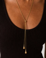 On-body macro of the Aurelia gold slider and two polished teardrops