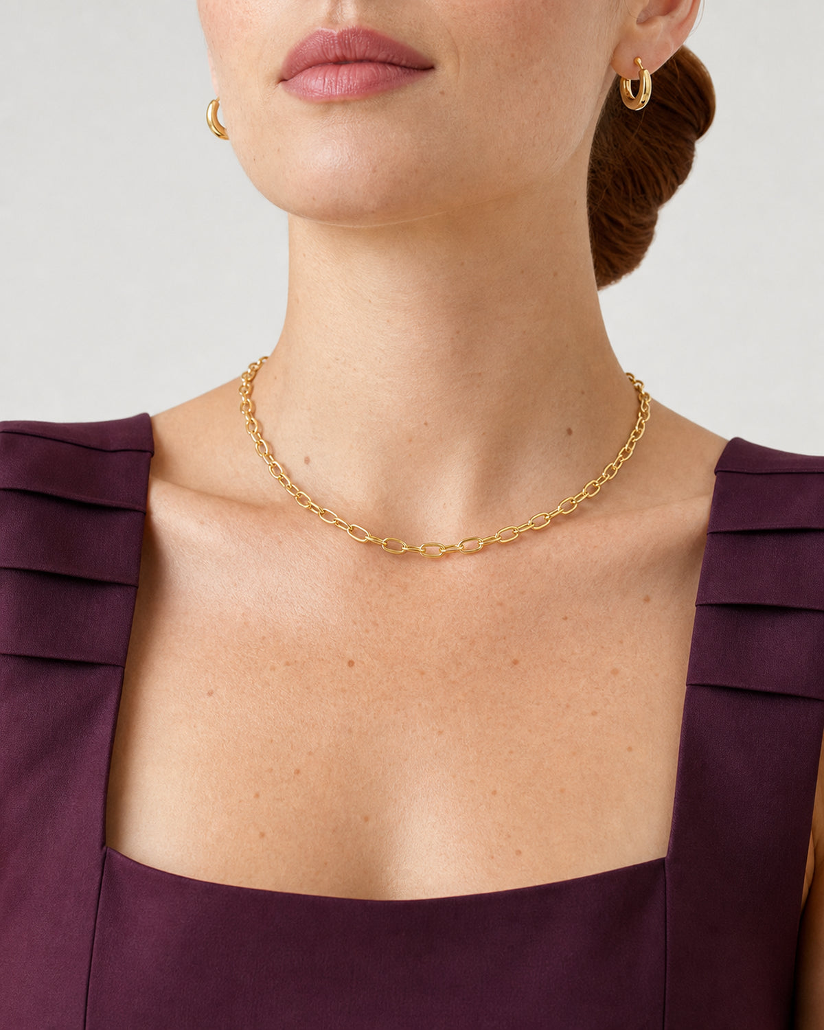 Mouth-down frontal view of the Aurelle gold oval-link necklace and sculpted hoops