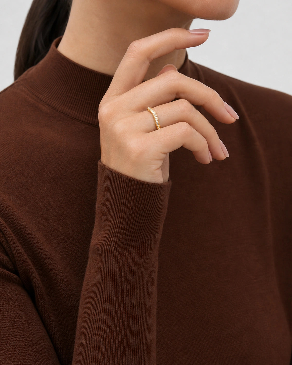 Aurelle gold pavé band worn with the hand arcing beneath the lower jaw