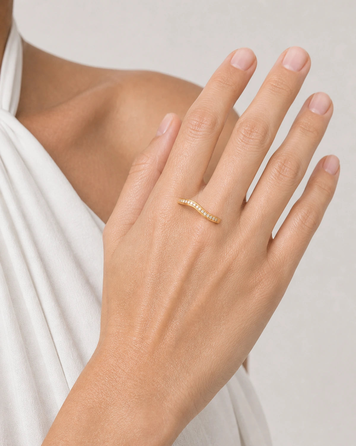Close wearing view of the Aurelle single-row wavy gold pavé band