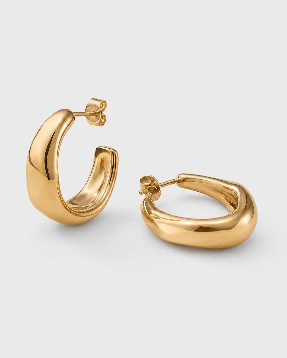 Pair of Aurelle gold sculpted hoops on a seamless pale dove-grey studio background
