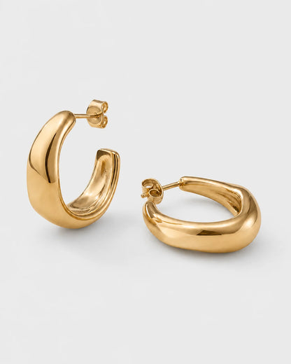 Pair of Aurelle gold sculpted hoops on a seamless pale dove-grey studio background