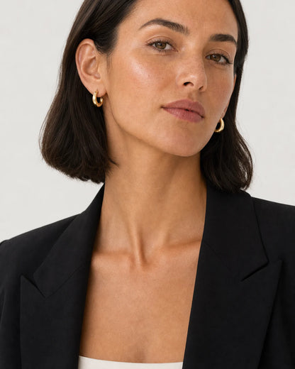 American model aged 26 to 29 wearing Aurelle sculpted hoops in a pale dove-grey studio
