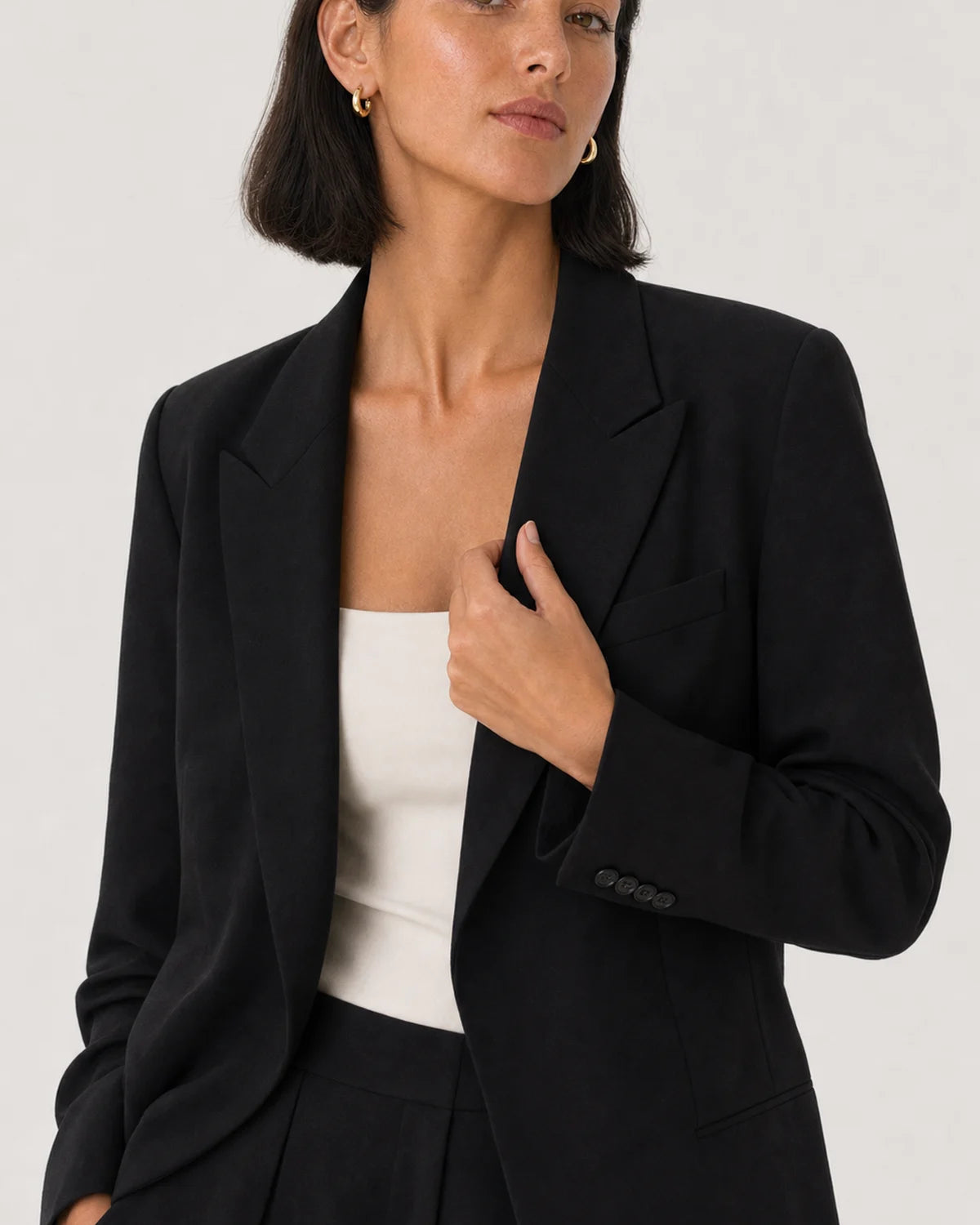 Wide editorial studio portrait showing the Aurelle sculpted hoops at natural scale