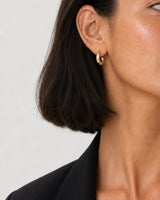 Clean on-ear close-up of one Aurelle gold sculpted hoop