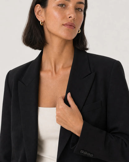 Human-scale styling view of the Aurelle sculpted hoops with black tailoring