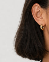 Extreme on-ear macro of the Aurelle sculpted gold hoop profile