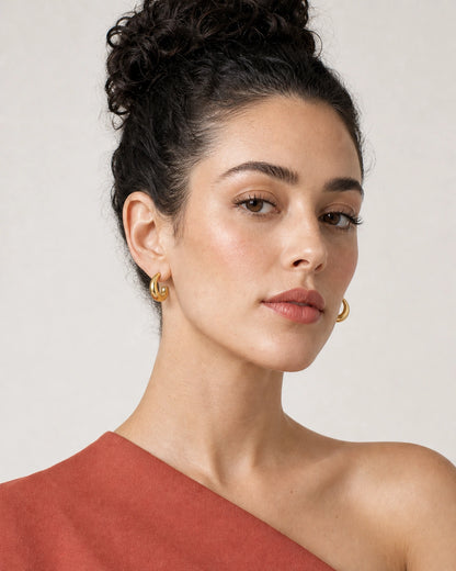Face portrait wearing the Aurelle gold sculpted open-C hoops with terracotta crepe