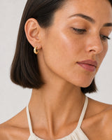Close wearing view of an Aurelle hand-sculpted gold open C hoop
