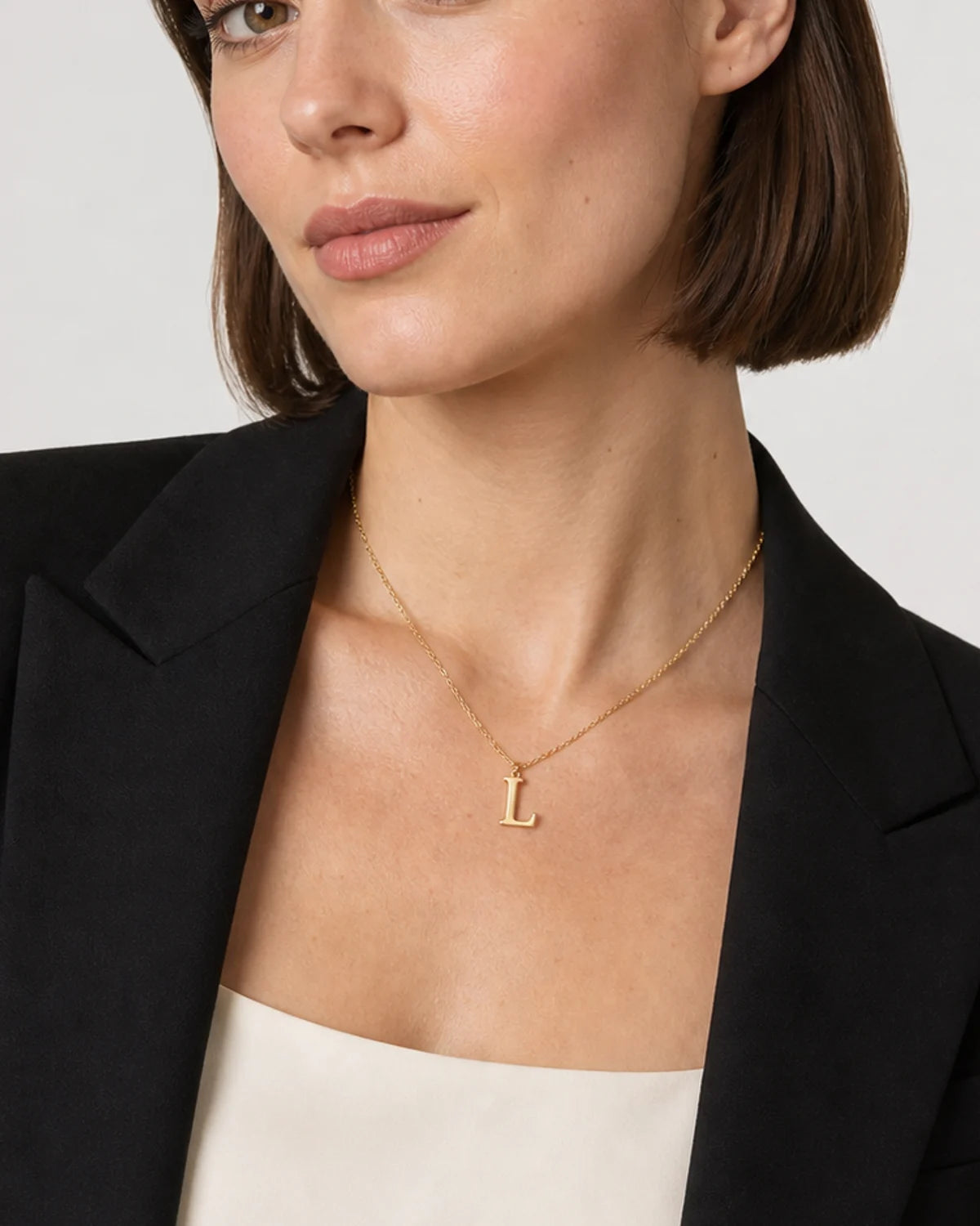Close on-body view of the Aveline gold serif L pendant and fine chain