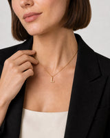 Human-scale detail of the model touching the Aveline necklace chain beside the L charm