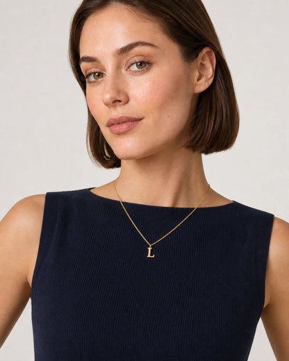 Model in a navy French Riviera knit top wearing the Aveline gold L necklace