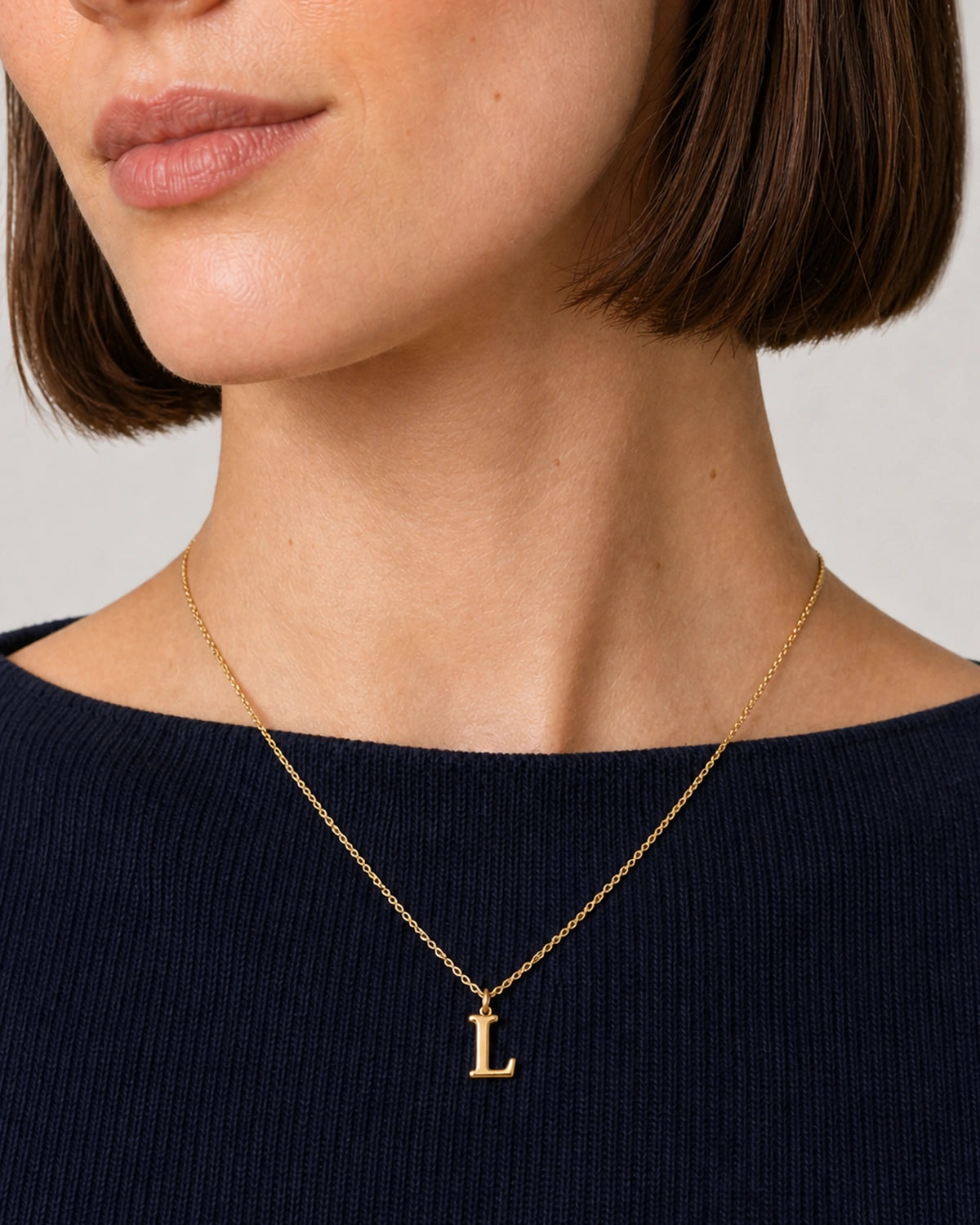 Close wearing view of the Aveline warm-gold serif L pendant