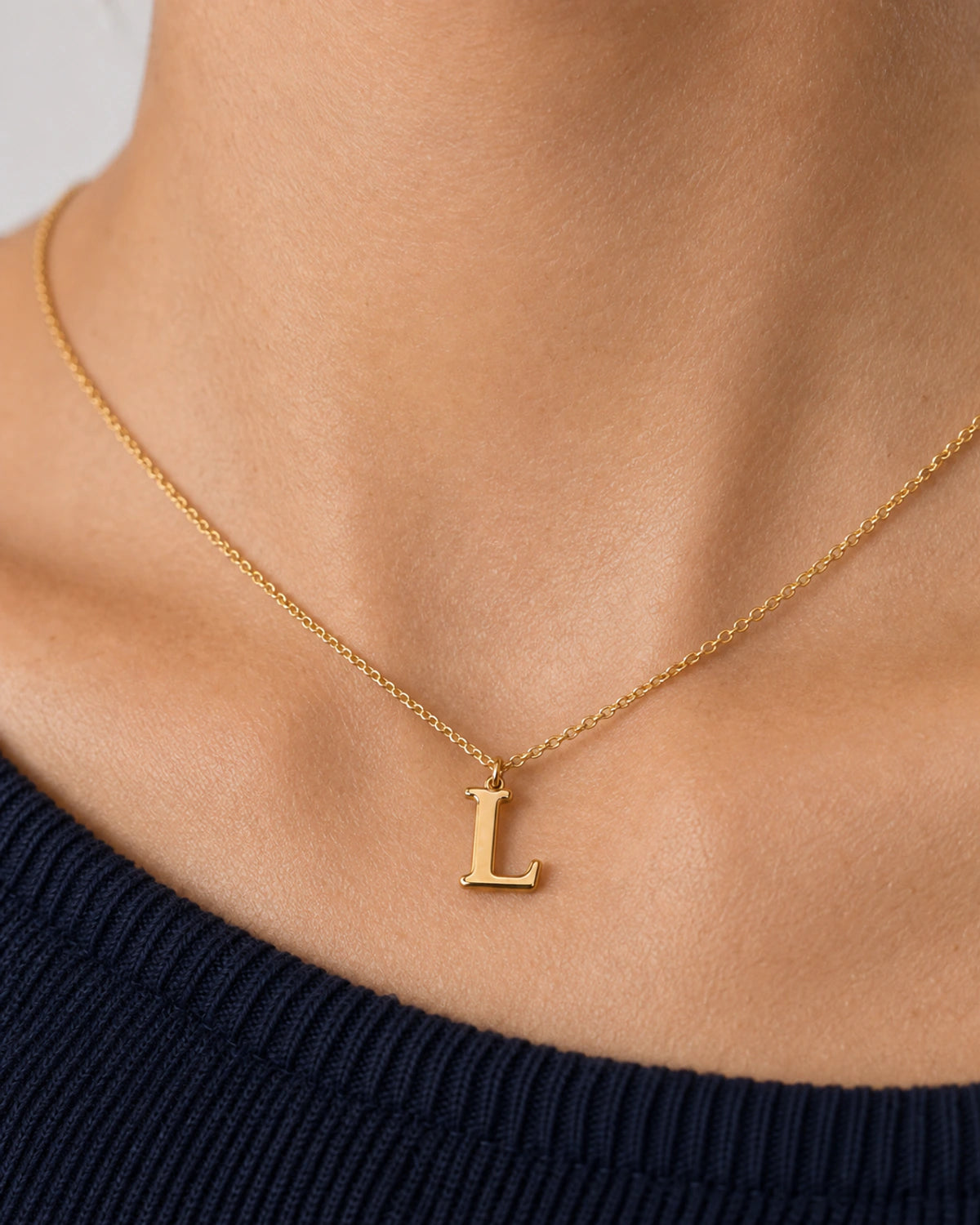 Extreme collarbone macro of the Aveline gold cable chain and serif L pendant