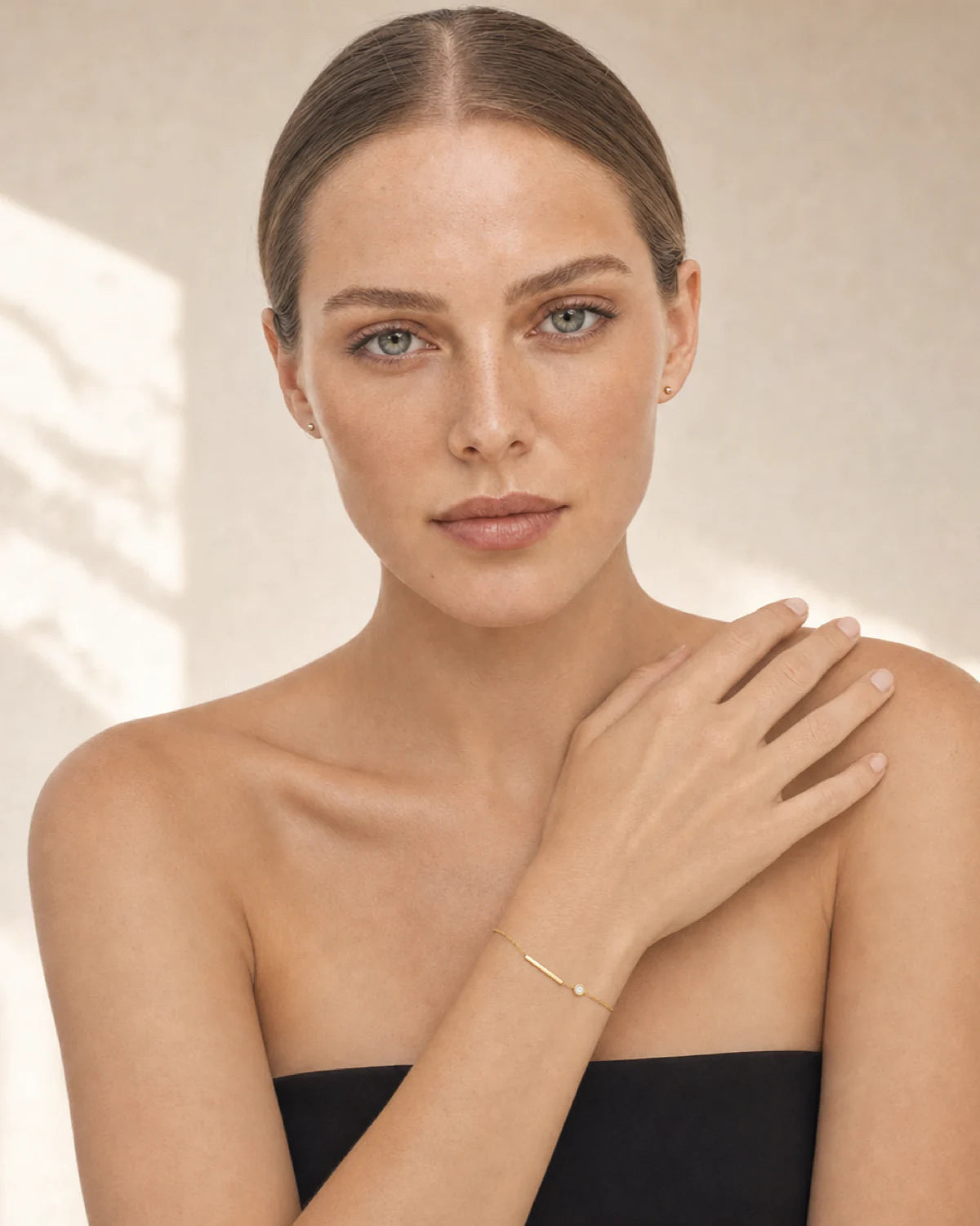 Caucasian model in black wearing Aven gold bracelet on her right wrist