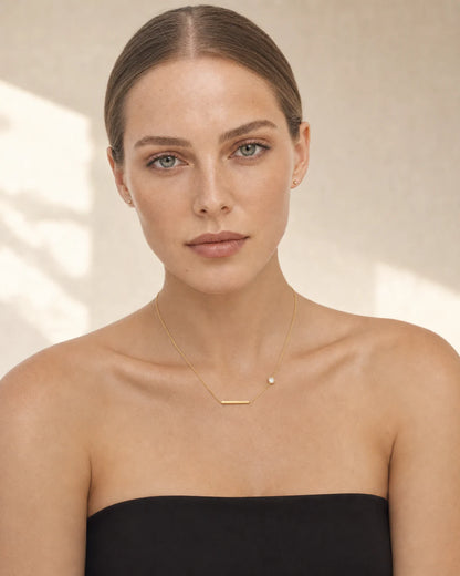 Caucasian model in black wearing the Aven gold station necklace