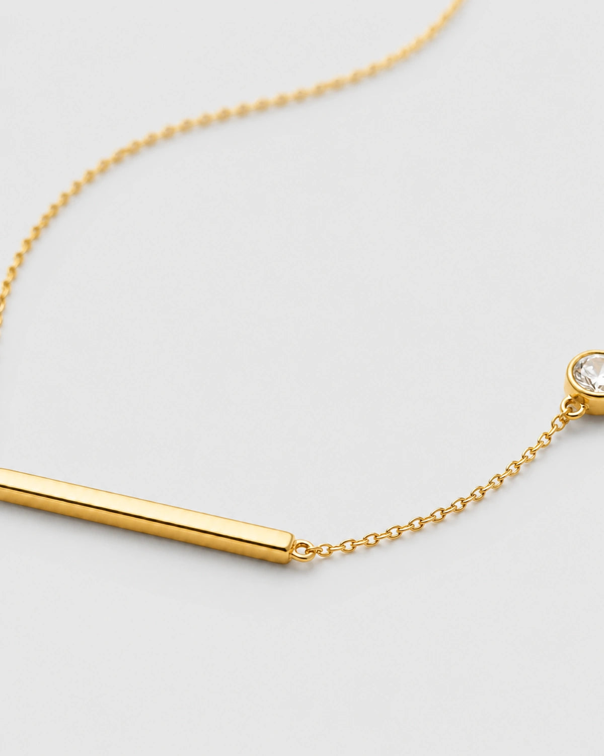 Macro of Aven polished gold bar and offset bezel zircon