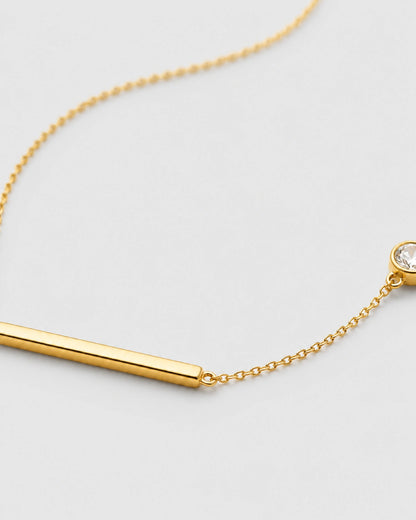 Macro of Aven polished gold bar and offset bezel zircon