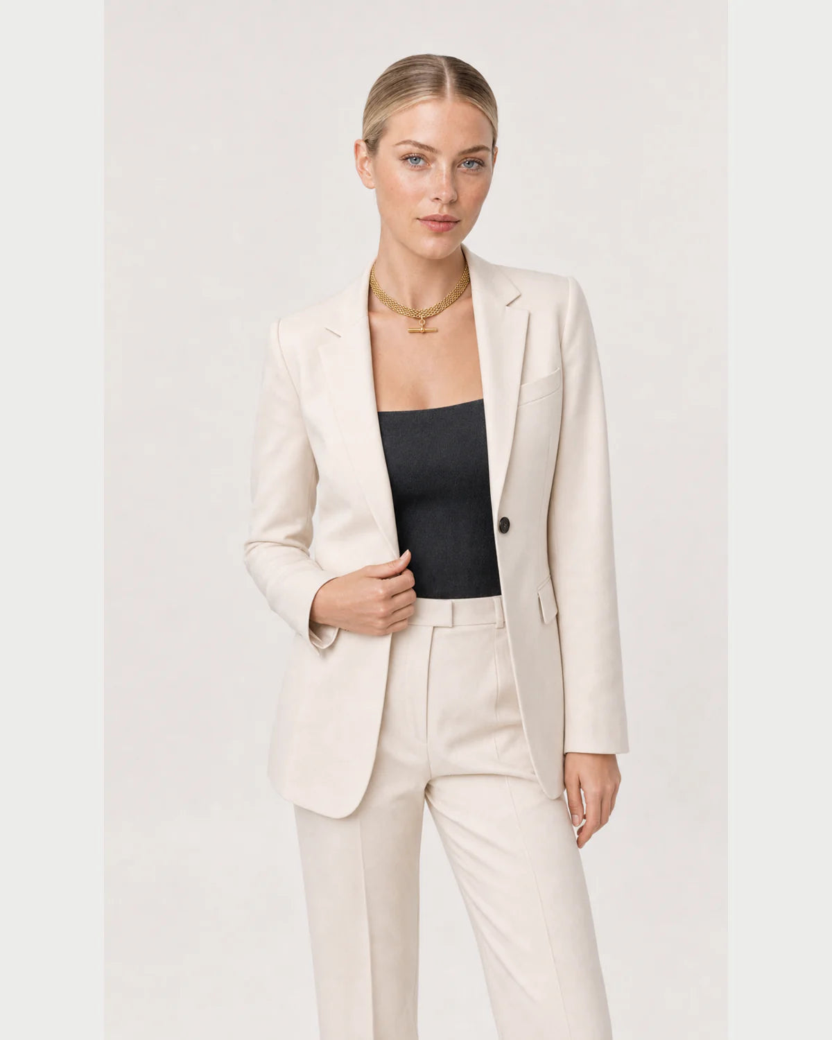 Wide grey-studio editorial portrait featuring the Camille T-bar collar