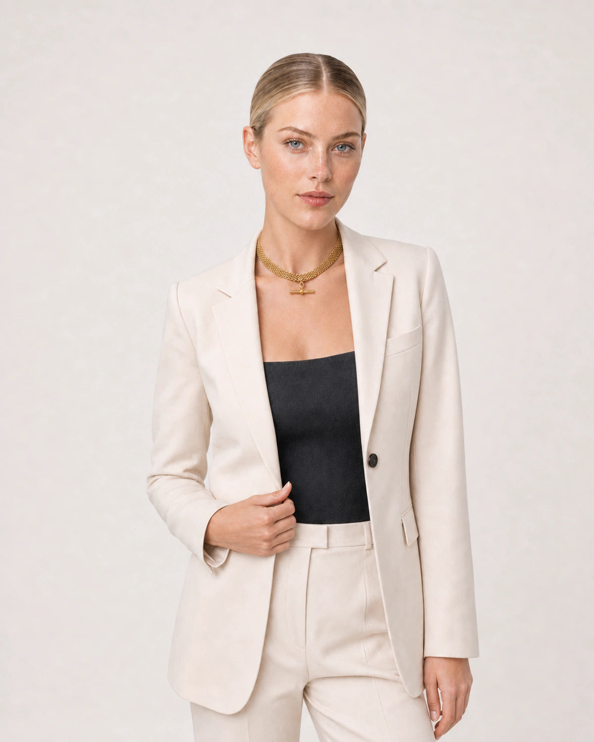 Wide grey-studio editorial portrait featuring the Camille T-bar collar