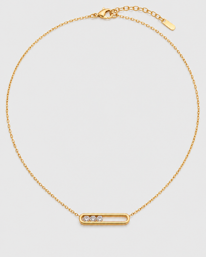 Celene gold floating crystal bar necklace on a seamless pale dove-grey studio background