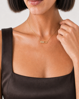 Human-scale detail of the model touching the Celene necklace chain beside the pendant