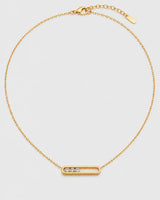 Celene gold floating-crystal bar necklace on a pale neutral-grey studio background
