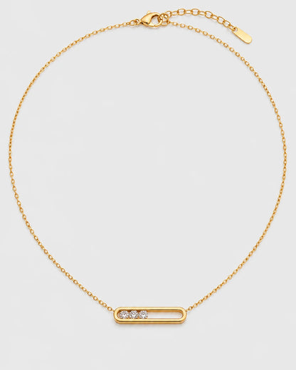 Celene gold floating-crystal bar necklace on a pale neutral-grey studio background