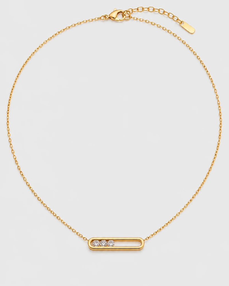Celene gold floating-crystal bar necklace on a pale neutral-grey studio background