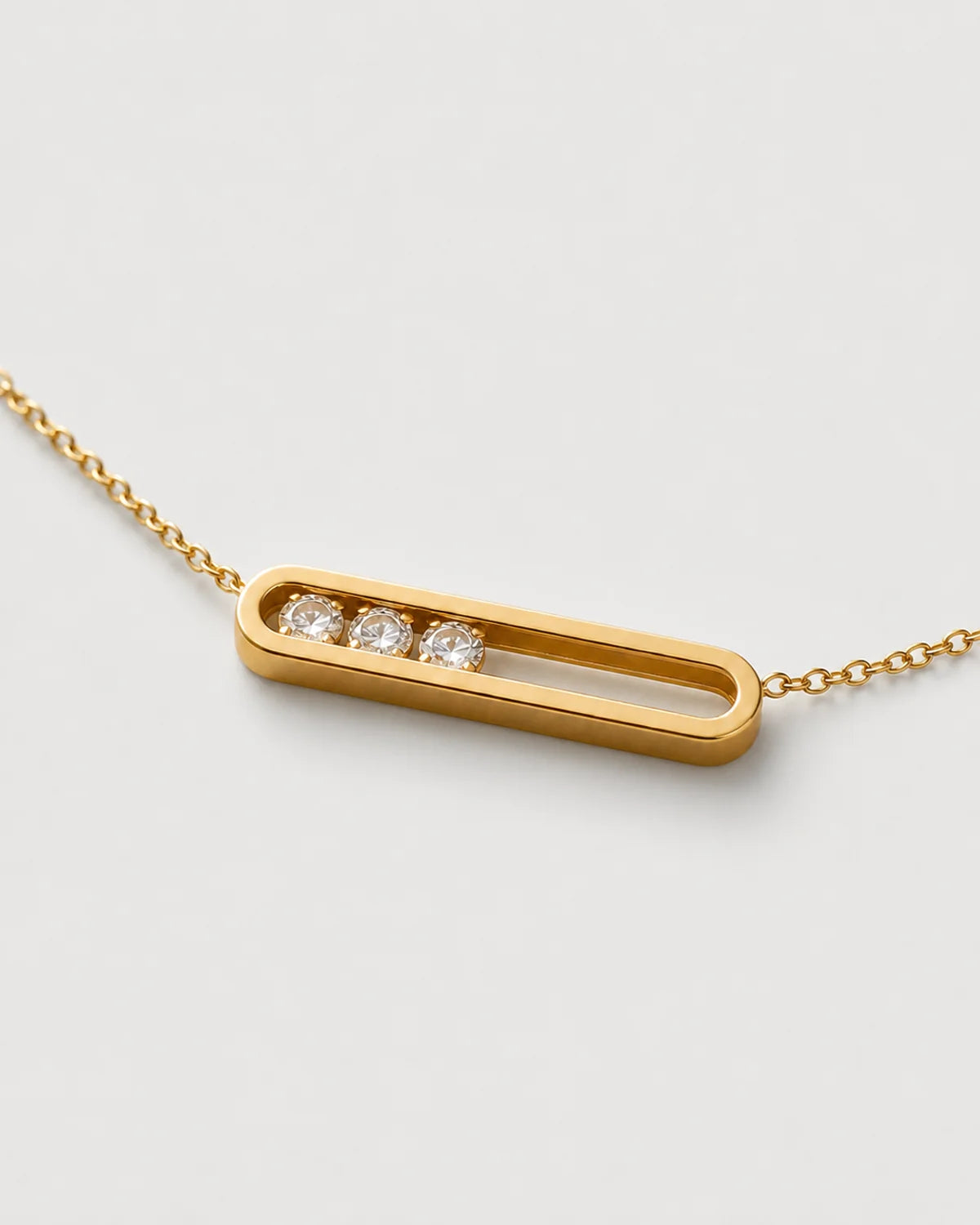 Macro of the Celene open gold bar with exactly three clear crystals grouped at one side