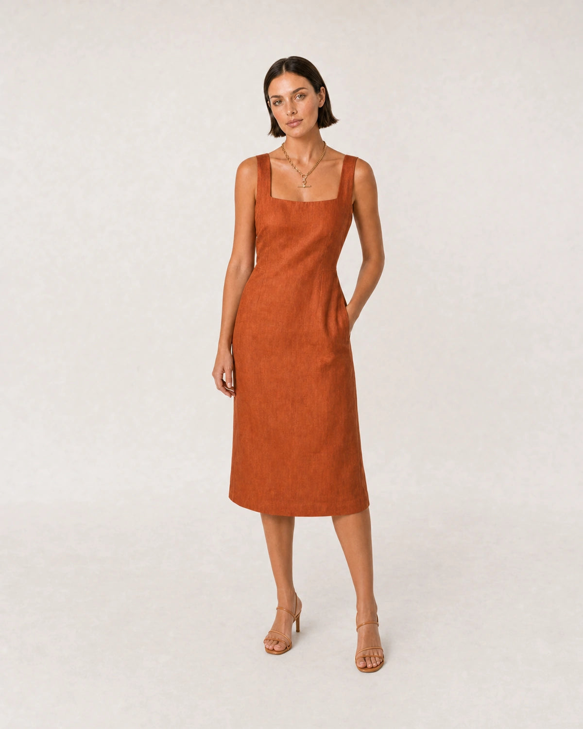 Wide studio portrait in a terracotta linen dress featuring the Célestine necklace