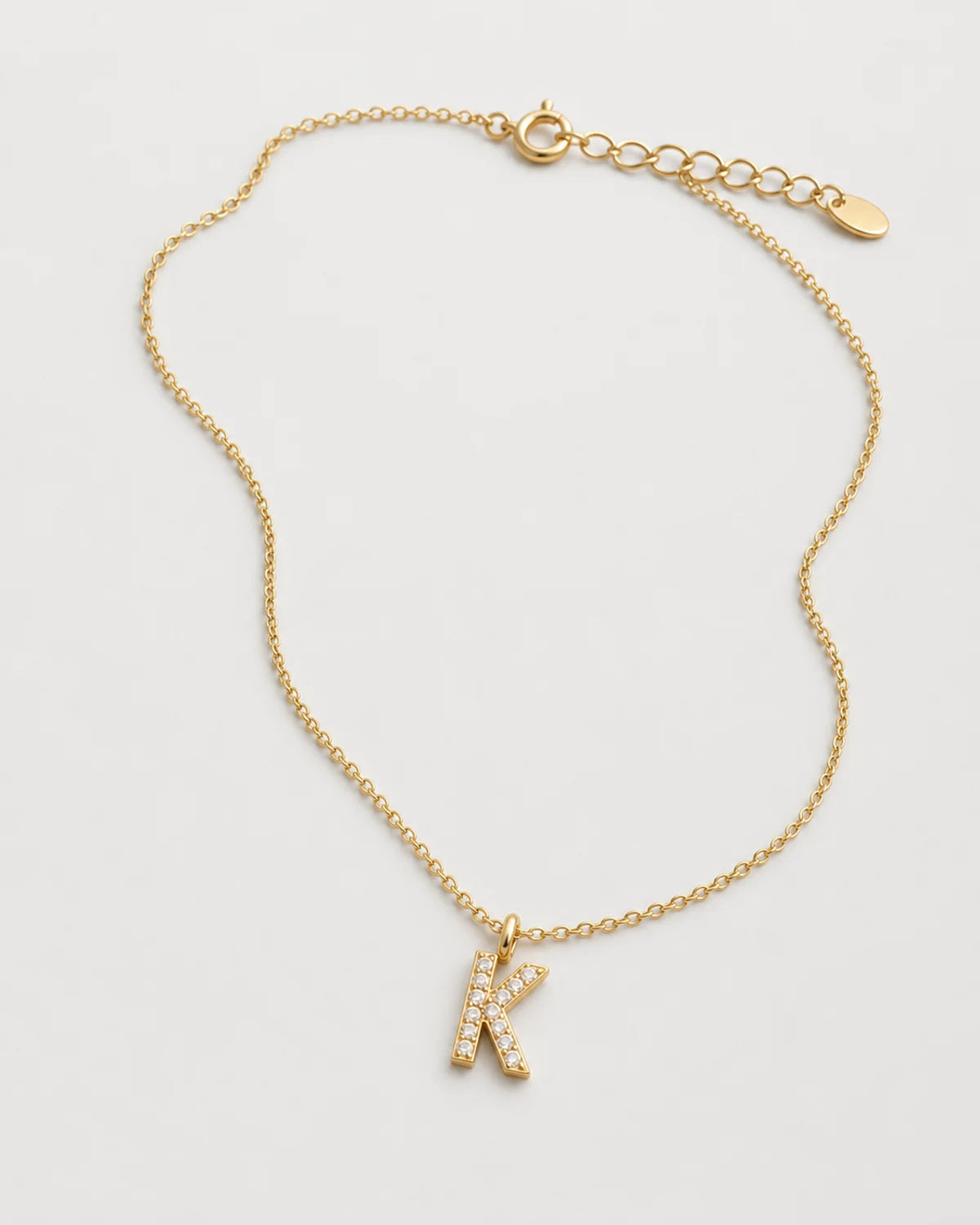 Alternate laid-out view of the Ciel pavé K necklace and oval end tag