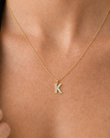 Extreme on-body macro of the Ciel clear-pavé K and fine gold chain