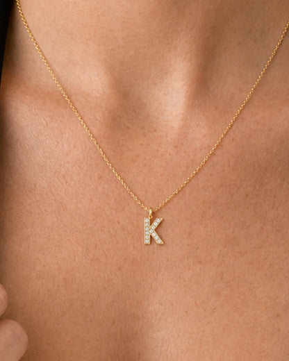 Extreme on-body macro of the Ciel clear-pavé K and fine gold chain