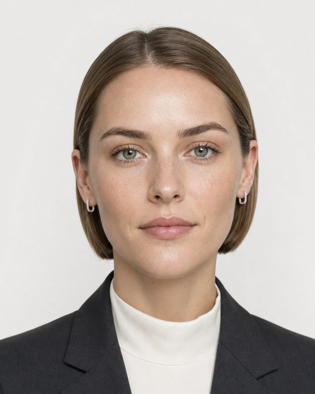 Model wearing the Clea silver crystal huggies in a pale dove-grey studio