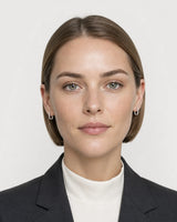 Model wearing the Clea silver crystal huggies in a pale dove-grey studio