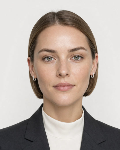 Model wearing the Clea silver crystal huggies in a pale dove-grey studio