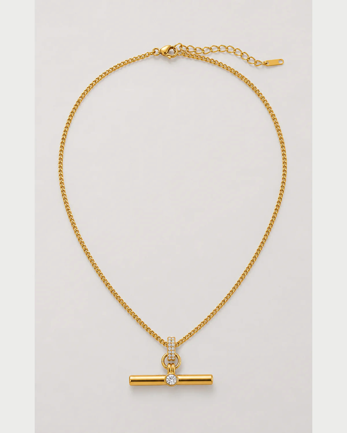 Delphine gold pavé toggle necklace on a pale dove-grey background